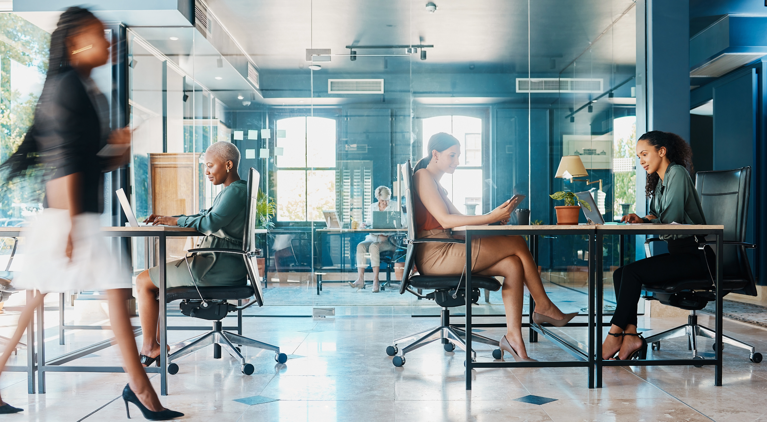Mehrere Damen im Businessoutfit arbeiten in einem offenen, modernen Büro.